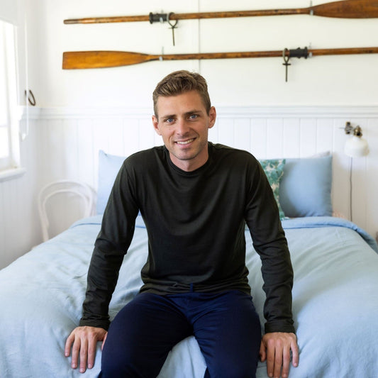 man sitting on bed wearing the best pajamas made from merino