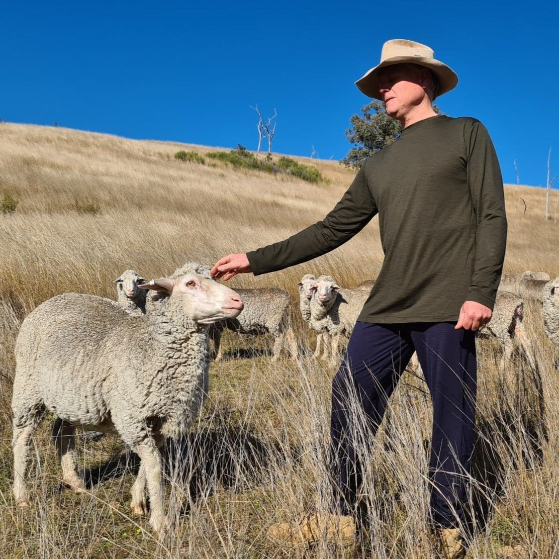 Murray patting sheep wearing Sleepy Merino sleep and lounge pants