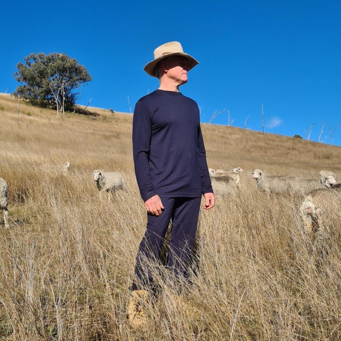 Founders brother in paddock with sheep wearing Sleepy Merino pyjamas