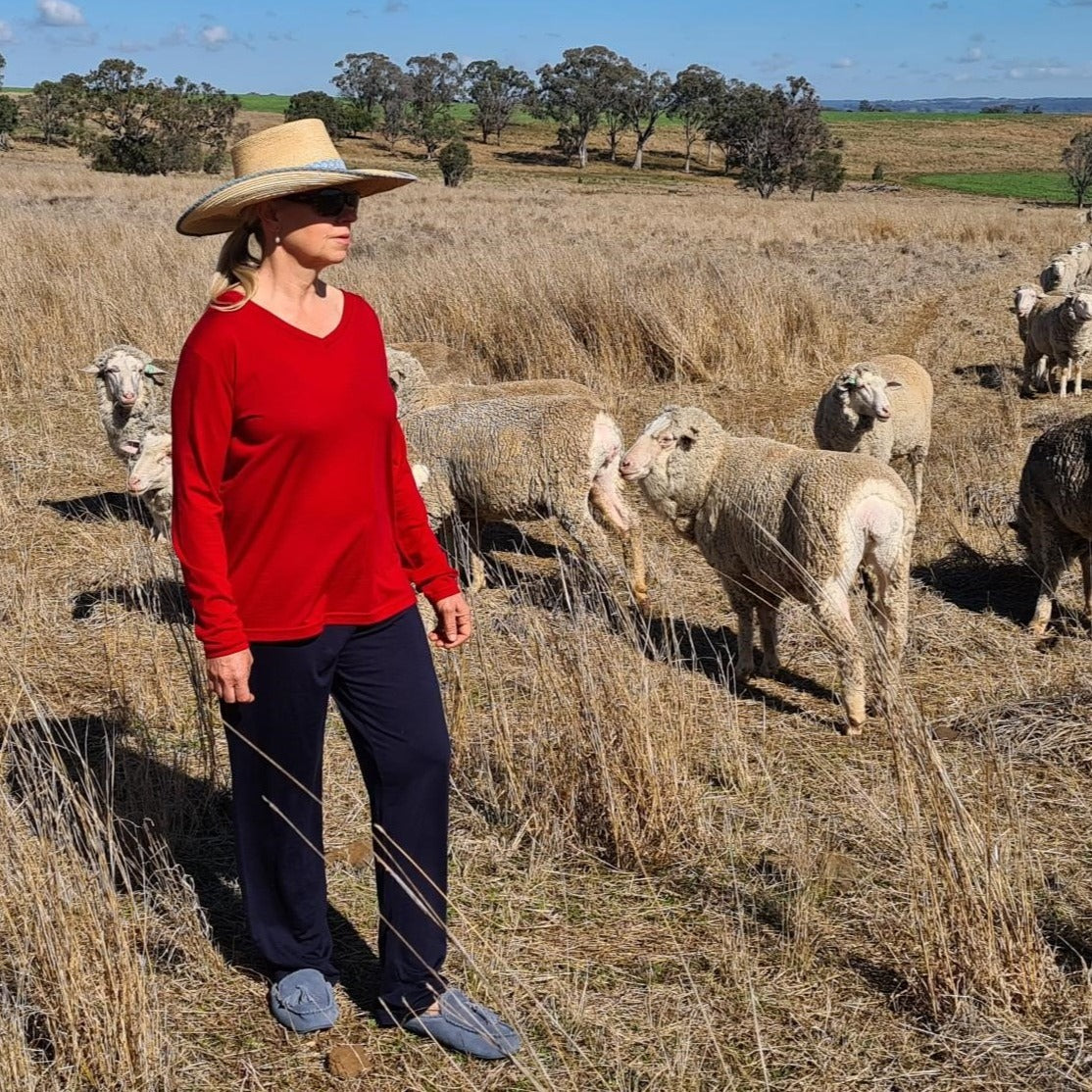 Julie in paddock with sheep wearing red Sleepy Merino tee